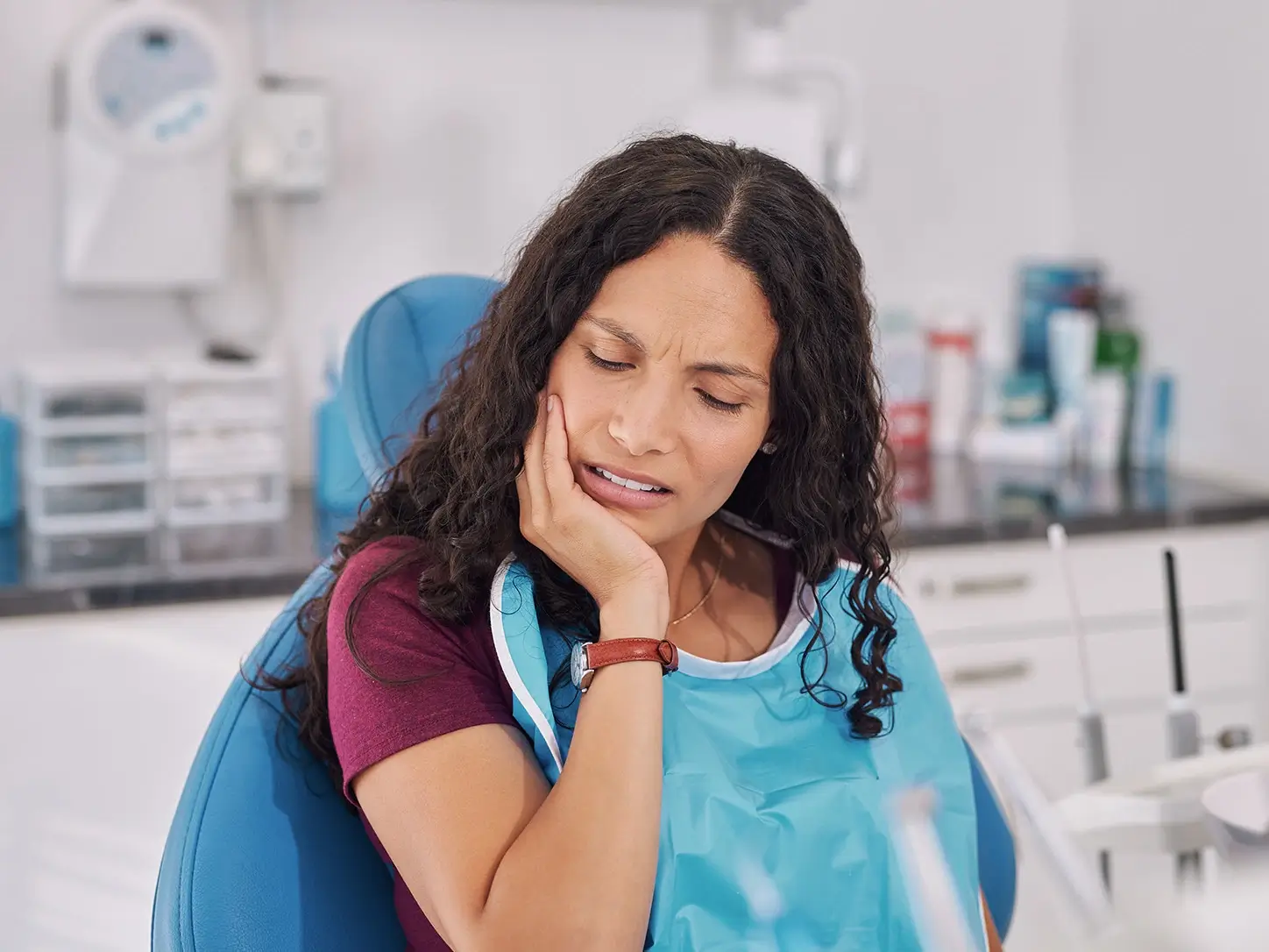 Woman holding her cheek in pain in a dental chair, waiting for same-day care from an emergency dentist in Louisville, KY